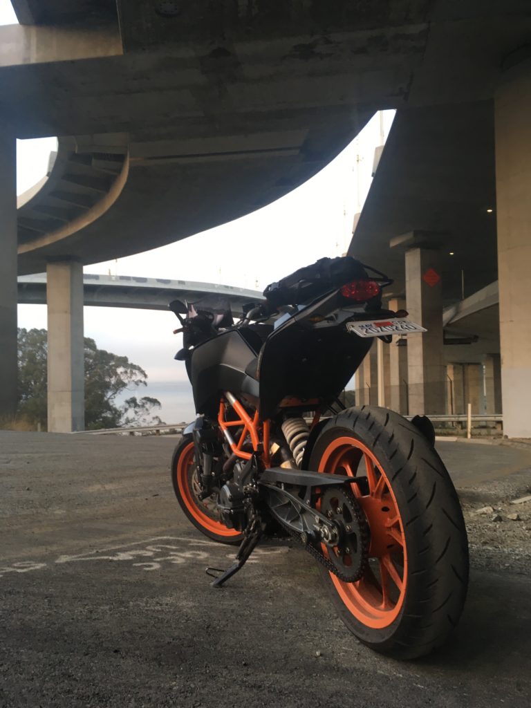 My 2015 KTM 390 Duke parked in front of the underpinnings of the Bay Bridge